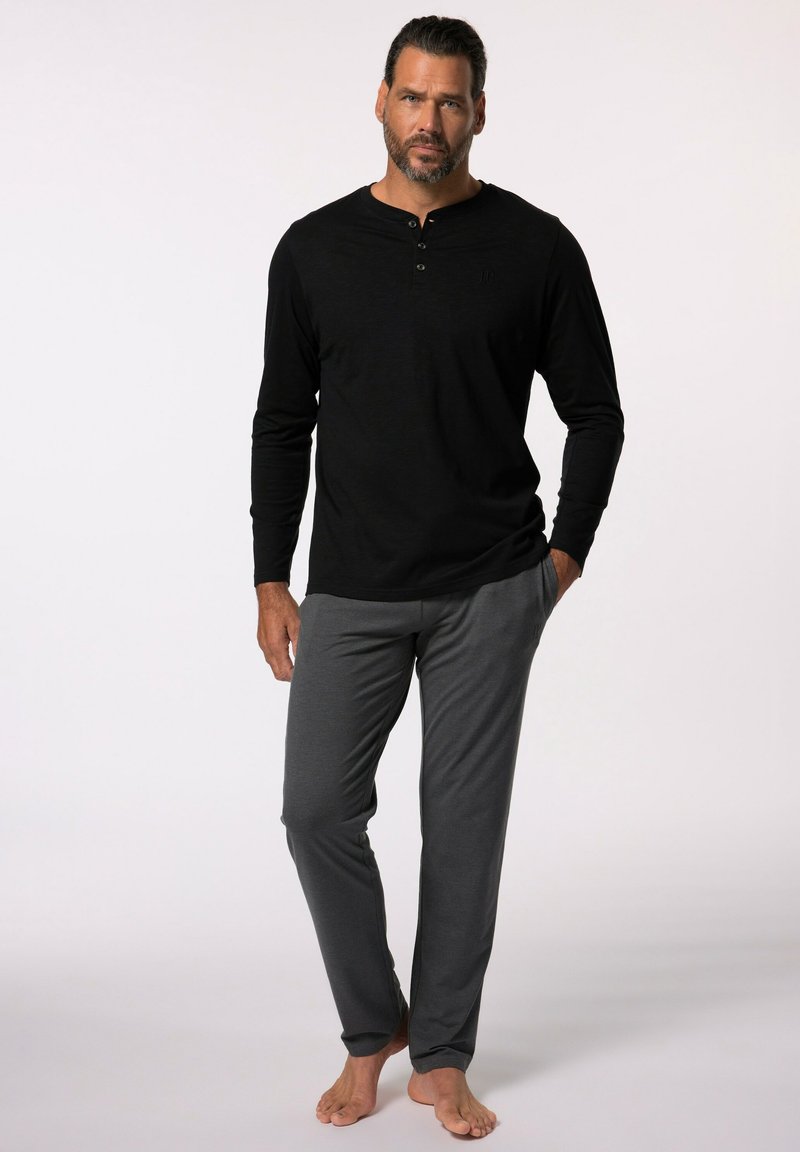 Schwarzes Langarm-Henley-Shirt mit drei Knöpfen, kombiniert mit grauen, leichten Lounge-Hosen. Beide Kleidungsstücke haben eine lockere Passform und eine glatte Textur.