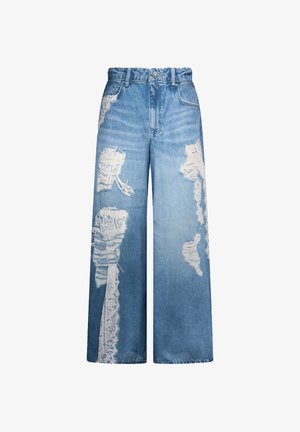 Jeans denim blu a gamba larga con vita alta, strappi e bordi sfrangiati che lasciano intravedere un tessuto in pizzo bianco sottostante.