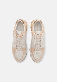 Licht beige sneakers met een bovenwerk van mesh en suede, ronde neus, platte vetersluiting en een rubberen zool met textuur en subtiele logo-details.