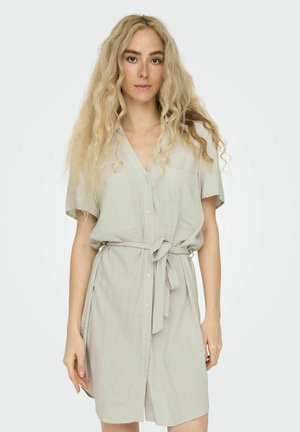 Robe chemise gris clair à manches courtes, avec un devant à boutons et une ceinture à la taille. Elle dispose de deux poches poitrine et d'une coupe décontractée. Texture de tissu lisse.