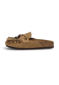 Mocasines de ante marrón sin cordones, con flecos y detalle de lazo, que cuentan con una plantilla de corcho y suela de goma texturizada para un mejor agarre.