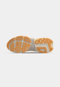 Semelle de chaussure en caoutchouc texturé avec un dessus beige. Des accents orange et un profil de semelle à motifs offrent adhérence et stabilité.