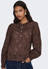 Braune bestickte Bluse mit Blumenmuster, strukturiertem Stoff, langen Puffärmeln, knöpfbarem Ausschnitt und detaillierten Nahtakzenten.