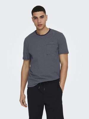 Camiseta de manga corta a rayas en azul marino y blanco, con un cuello redondo y un bolsillo de parche en el lado izquierdo, combinada con pantalones oscuros.