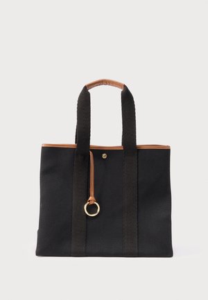 Sac cabas noir avec garniture en cuir marron, deux longues poignées et une lanière en cuir ornée d'un anneau doré suspendu à l'avant.
