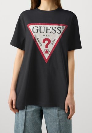 T-shirt en coton noir avec un grand graphique triangulaire rouge et blanc affichant "GUESS U.S.A." et un point d'interrogation au centre.