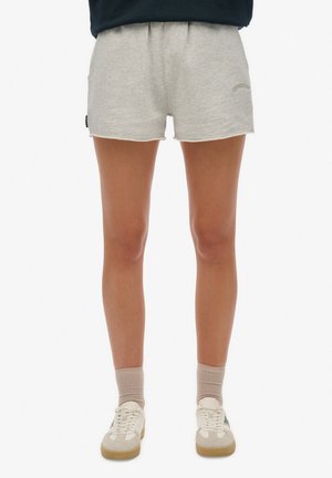 Grijze katoenen shorts met een elastische tailleband, een onbewerkt zoom en een klein logo op de voorkant. G gedragen met witte en beige sneakers en beige sokken.