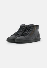 Black high-top sneakers made of textured leather, featuring a side zipper, laces, and a rubber sole. Sparkly fabric at the collar adds detail.