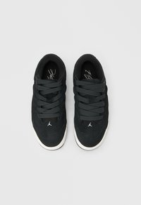 Ζευγάρι μαύρα χαμηλά αθλητικά παπούτσια με χοντρές κορδόνια και λευκές μεσαίες σόλες, απεικονιζόμενα από πάνω σε ανοιχτό γκρι φόντο.