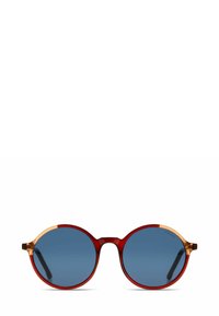 Lunettes de soleil rondes avec monture rouge, verres bleus et accents jaunes translucides sur les branches. Finition lisse et brillante.