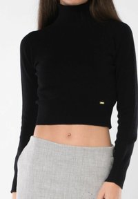 Maglione corto nero realizzato in tessuto morbido, con colletto alto, maniche lunghe e un piccolo logo dorato sul bordo inferiore.