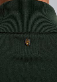 Dunkelgrüner Pullover mit gerippter Textur und umgeschlagenem Kragen. Ein schwarzes Badge mit "PME Legend" in Orange ist auf der Rückseite angebracht.