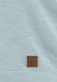 Maglione in cotone azzurro chiaro con tessuto testurizzato. Notevole patch in pelle marrone con logo sulla parte anteriore, con lettering e logo in rilievo.