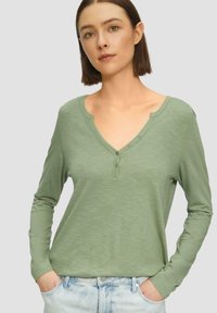 Langarm, V-hals shirt in lichtgroen, gemaakt van zachte stof met een subtiele textuur, beschikt over een knoopsluiting en een losse pasvorm.