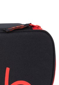 Schwarze Stofftasche mit rotem Reißverschluss und Akzenten. Vorn befindet sich ein auffälliges rotes Logo und die Oberfläche hat eine glatte Textur. Kompakte rechteckige Form.