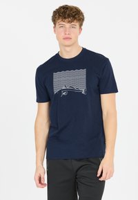 Marinblå bomullströja med en vit grafik av en fisk ovanför vågiga linjer. Korta ärmar och rund halsringning, standard passform.