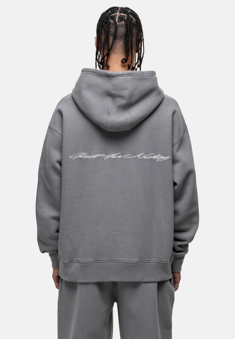 Felpa grigia con un grande cappuccio, vestibilità oversize, polsini e orlo a coste. Presenta testo bianco in corsivo sul retro. Tessuto morbido e resistente.