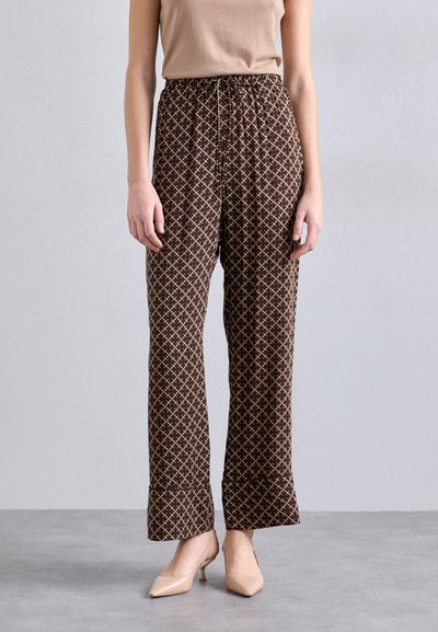 Pantaloni maro cu un model relaxat, având un design cu diamante și un tiv elastic, asortați cu tocuri nude.