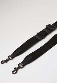 Curea neagră cu un corp textil și accente din piele, cataramă ajustabilă și clipsuri metalice la ambele capete. Textură netedă cu un design durabil.