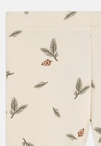 Korsettleggings i off-white med et trykk av furunåler og furu-kongler i mørkegrønn og brun. Myk tekstur med elastisk liv.