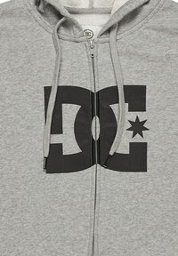 Sudadera gris con cremallera, hecha de material suave, que cuenta con un gran logotipo negro de DC con una estrella, capucha ajustable con cordón y cremallera frontal.