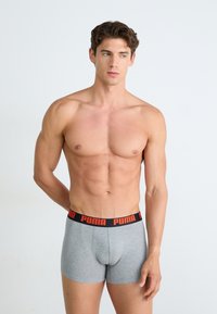 Boxeri gri din material elastic cu talie neagră, având branding roșu "PUMA"; fabricați dintr-un material moale și elastan pentru confort și susținere.