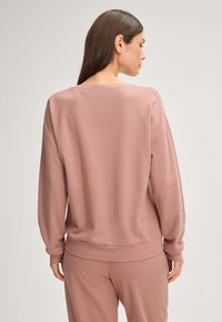 Lichtroze crewneck sweatshirt met lange mouwen, geribde boorden en onderkant; gemaakt van zachte stof, met een ontspannen pasvorm en een gladde textuur.