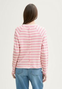 Camisa de manga larga a rayas en rosa claro con cierre de botones en la parte posterior, hecha de una tela suave. Cuenta con mangas raglán y un ajuste relajado.