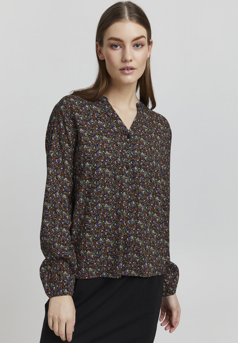Svart bluse med blomsterprint i flere farger. Har V-hals og lange pufferm med tettsittende mansjetter. Lett stoff.