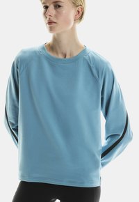 Sweat-shirt bleu clair avec des manches raglan, un col rond et des bandes noires sur les côtés. Tissu doux avec une texture lisse.