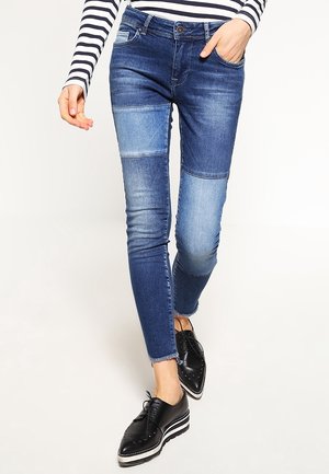 Slim-fit patchwork blue denim jeans worn with striped long-sleeve top and black platform brogue shoes.