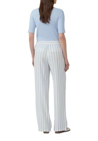Top a maniche corte ribbed di colore azzurro chiaro abbinato a pantaloni larghi a righe bianche e azzurre con elastico in vita e tasche.