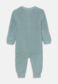 Macacão de bebé em malha azul claro, com mangas longas e punhos canelados, mostrado de costas sobre um fundo branco.