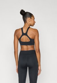 Μαύρο αθλητικό μπουστάκι με σχέδιο racerback, με άνοιγμα σε σχήμα κλειδιού και απαλό ύφασμα. Συνδυάζεται με μαύρο κολάν ψηλής μέσης.