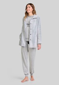 Abrigo de patrón espiga gris con botones, combinado con una sudadera gris con texto y pantalones de chándal a juego con puños elásticos.