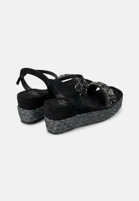 Sandali wedge neri in suede con accenti metallici decorativi, cinturini regolabili e una piattaforma tessuta e strutturata. Adatti per l'abbigliamento casual.