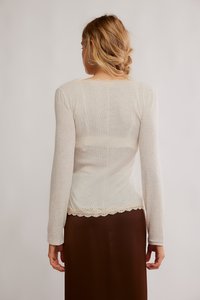 Gaiši bēšs garām piedurknēm topiņš ar rāvējslēdzēja faktūru un izgrieztu mežģīņu apakšmalu. Aizmugure ir gluda, ar vienkāršu apaļu kakla izgriezumu.