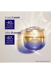 Shiseido Vital Perfection -voidepurkki, jossa on kullan ja sinisen liukuväri, sileä pinta, kaareva muoto ja valkoinen kermavaahtomainen pinta.