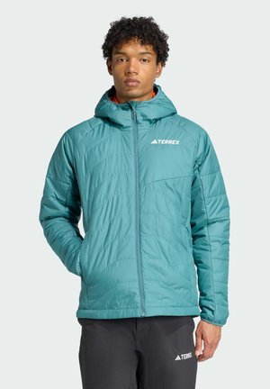 Chaqueta aislante en color azul verdoso con cremallera frontal, capucha y bolsillos laterales. Presenta patrones de costura diagonal y un logo en el lado izquierdo del pecho.
