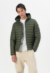 Olive green puffer jacket with horizontal quilted design, zippered front, and adjustable hood. Light fabric with a smooth texture.