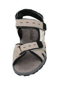 Beige sandal med svarta accenter, justerbara remmar och en vadderad sula. Har perforeringar för andningsförmåga och en gummisula.