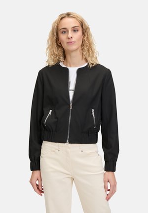 Veste bomber noire cropped avec une fermeture éclair à l'avant, deux poches latérales et des poignets élastiques. Matière lisse avec une coupe ajustée.