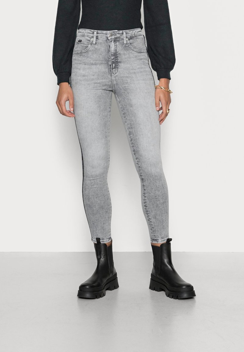 Grå skinny jeans med en blekt tvätt, fem fickor, kontrasterande sömmar och en medelhög midja, kombinerat med svarta ankelstövlar.