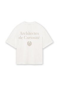 Valge puuvillane T-särk lühikeste varrukatega, millel on kuldsete tähtedega kiri "Architectes de Curiosité" ja dekoratiivne lehegraafika all.