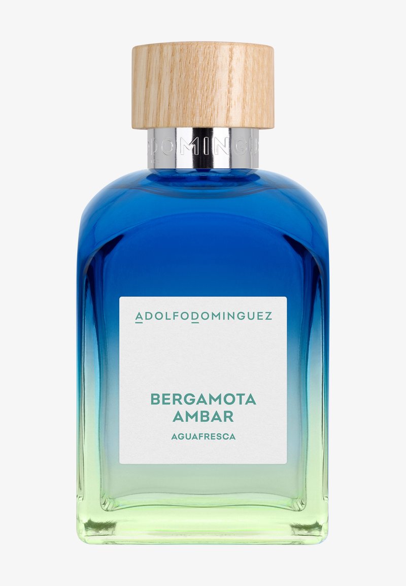 Flacon de parfum en verre ombré du bleu au vert avec un bouchon en bois, étiqueté « Adolfo Dominguez Bergamota Ambar Aguafresca. »