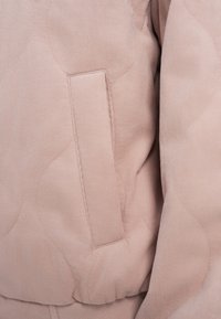 Φωτεινό ροζ σακάκι από κορντόρι με καπιτονέ σχέδιο και οριζόντια τσέπη στην αριστερή πλευρά, που ξεχωρίζει για την απαλή υφή και τη διακριτική λάμψη.