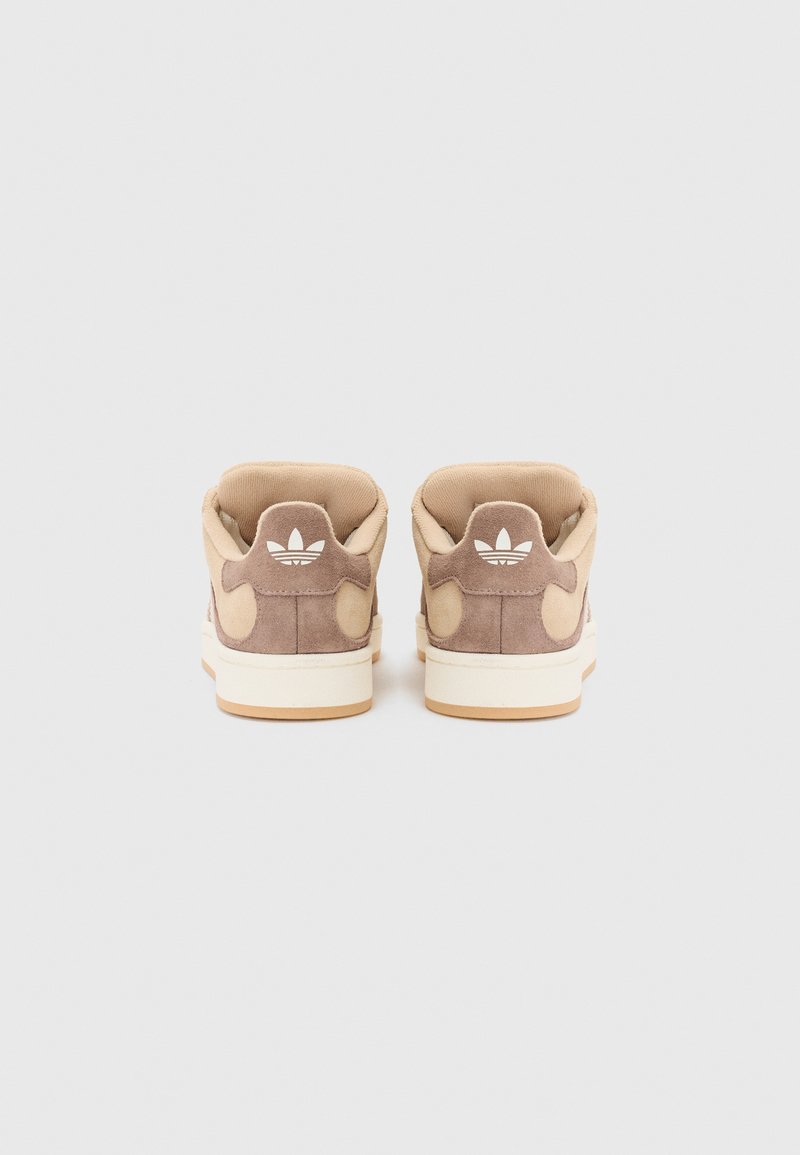 Baskets montantes en daim marron avec des accents beiges, détail de logo blanc au talon et semelle en caoutchouc crème. Texture lisse avec un col rembourré.