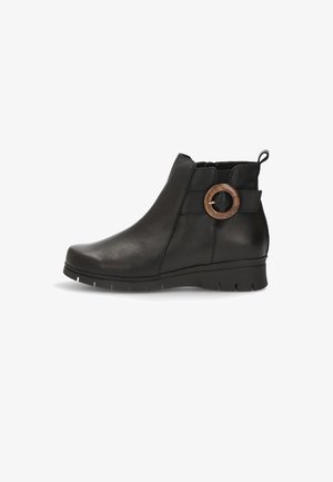 Botín de cuero negro hasta el tobillo con punta redondeada, paneles elásticos laterales y un acento circular de madera en la correa. Suela baja y texturizada para agarre.