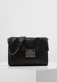 Czarna torebka z geometrycznymi wzorami zamszu i tkaniny o fakturze, metalowym zamkiem oraz paskiem na łańcuszku. Gładkie wykończenie z błyszczącymi akcentami.