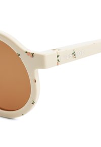 Runda solglasögon med en krämfärgad ram, prydd med persika- och gröna blomster mönster. Bruna tonade linser; varumärkesnamnet "LIEWOOD" är synligt.